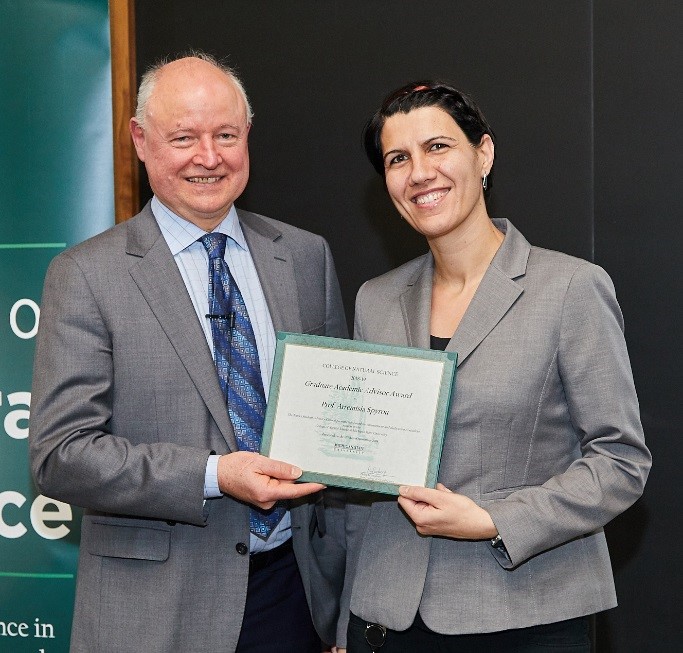 Artemis shaking hands and accepting the award from Dean Duxbury, both are smiling. 